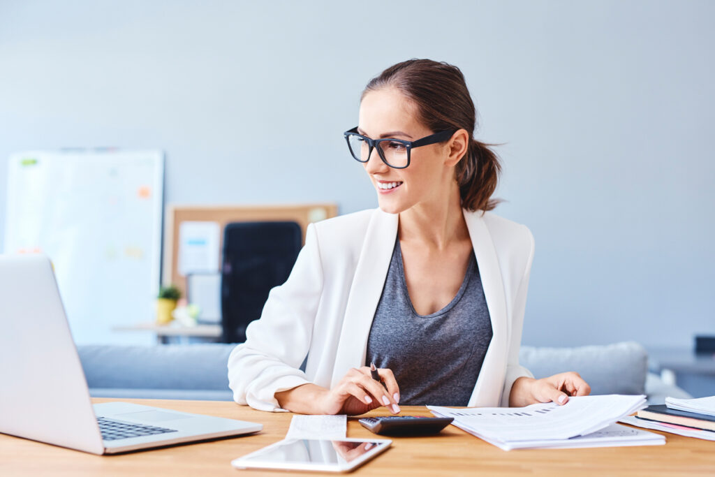 Professional woman working at a desk with a laptop, documents, and a smartphone.