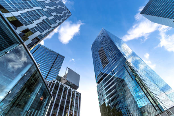 Low-angle view of modern skyscrapers with glass facades against a clear blue sky, showcasing contemporary urban architecture.