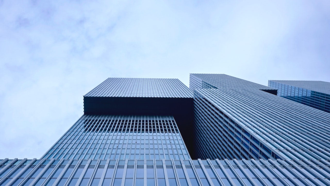 Modern skyscraper with a grid-patterned facade reaching into a sky crowded with cloud-based budgeting.