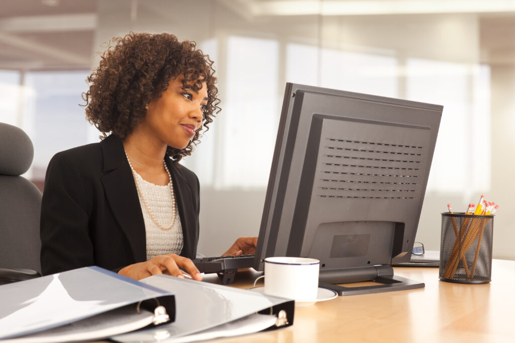 Professional woman working at a desk with a computer in an office setting.