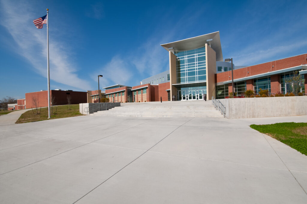 Modern school building with flagpole and clear blue sky.