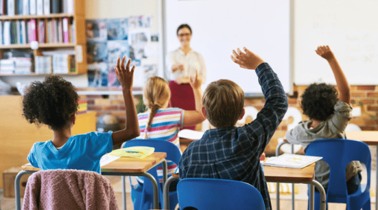 children raising hands in classroom