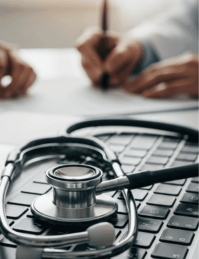 healthcare worker filling out paperwork by laptop