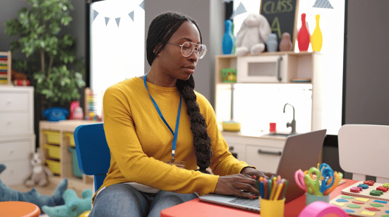 preschool teacher using laptop at kindergarten